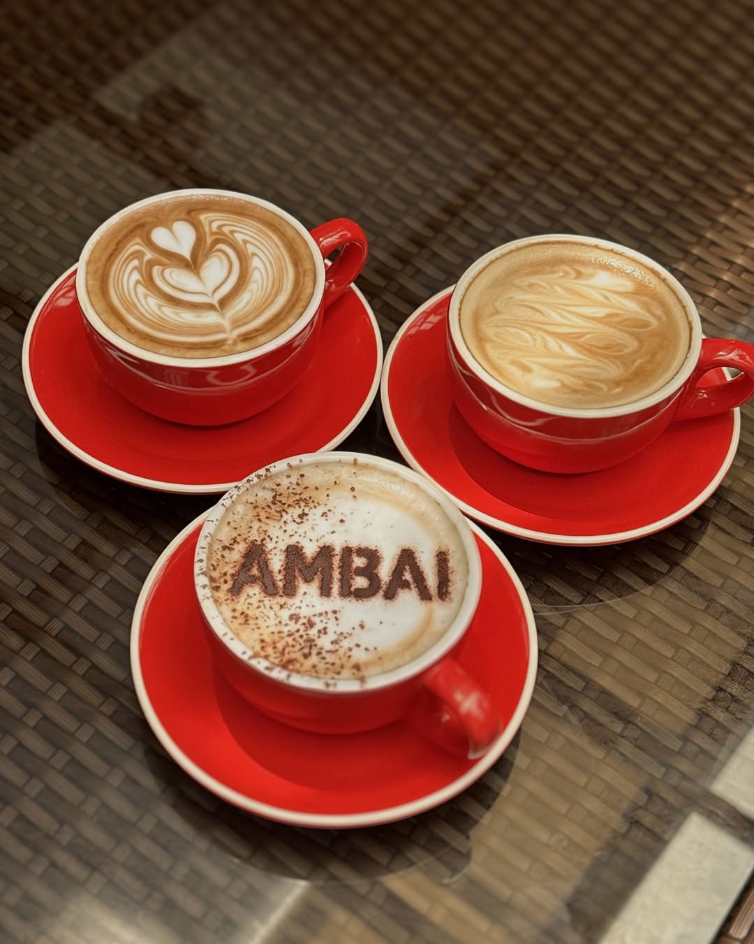 Three AMBAI coffees with latte art in red cups